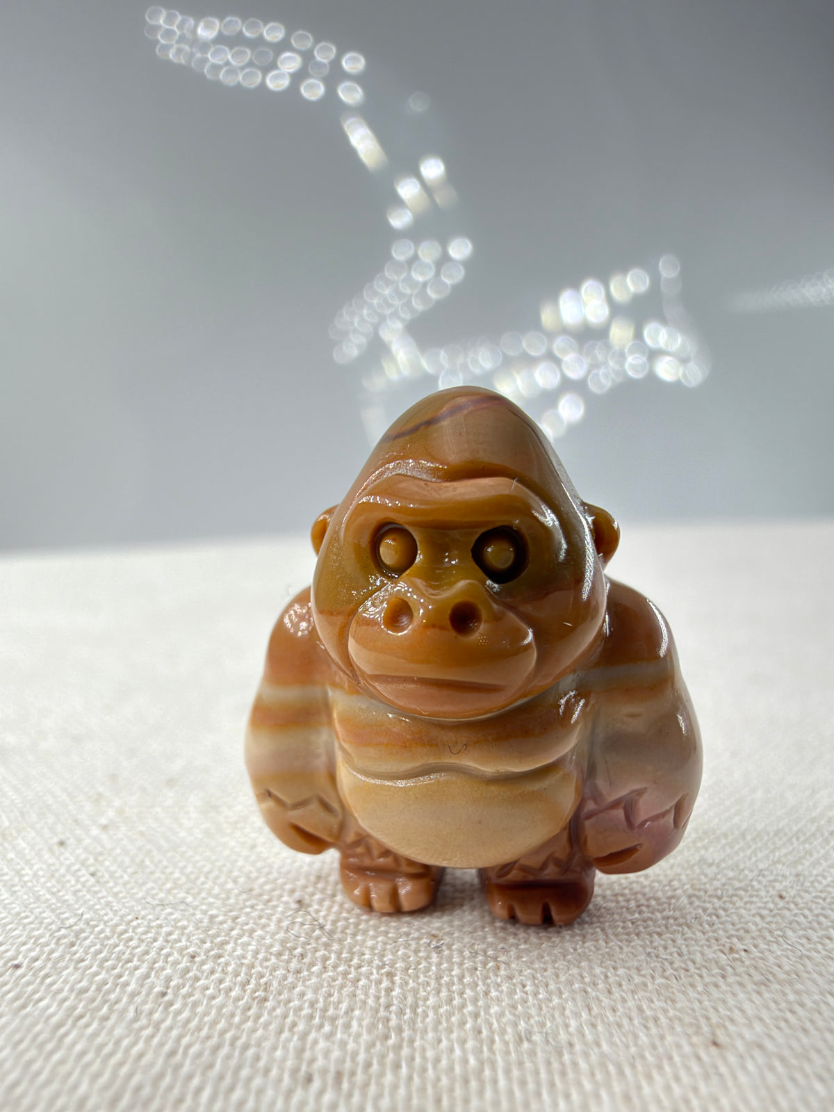 polierte Gorilla-Figur aus Alashan-Achat, in Braun und Creme, auf hellem Untergrund