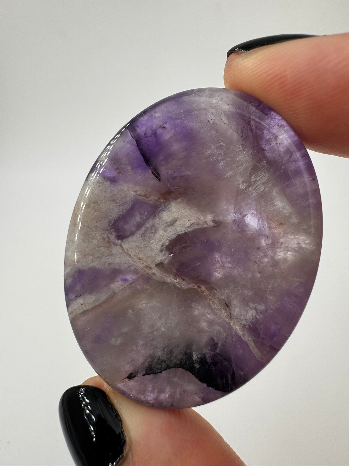 Ein Daumensteinen aus Amethyst mit glänzend polierten Oberflächen und zentraler Daumenmulde.