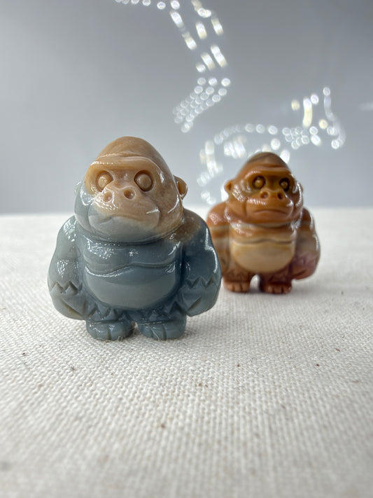 polierte Gorilla-Figuren aus Alashan-Achat, eine in Graublau und Beige, die andere in Braun und Creme, auf hellem Untergrund