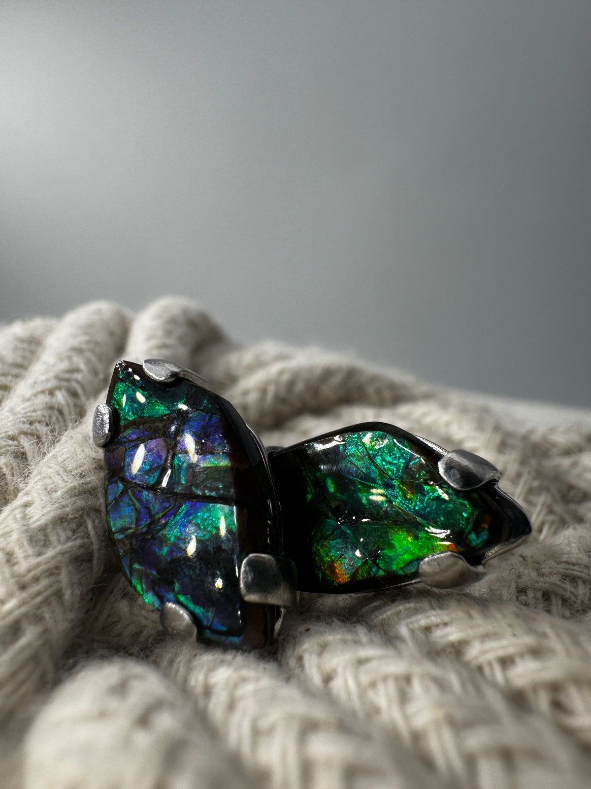 Ohrstecker aus Ammolith in Silberfassung, 1,8 × 1 cm, mit irisierendem Farbenspiel in  Grün und Blau.