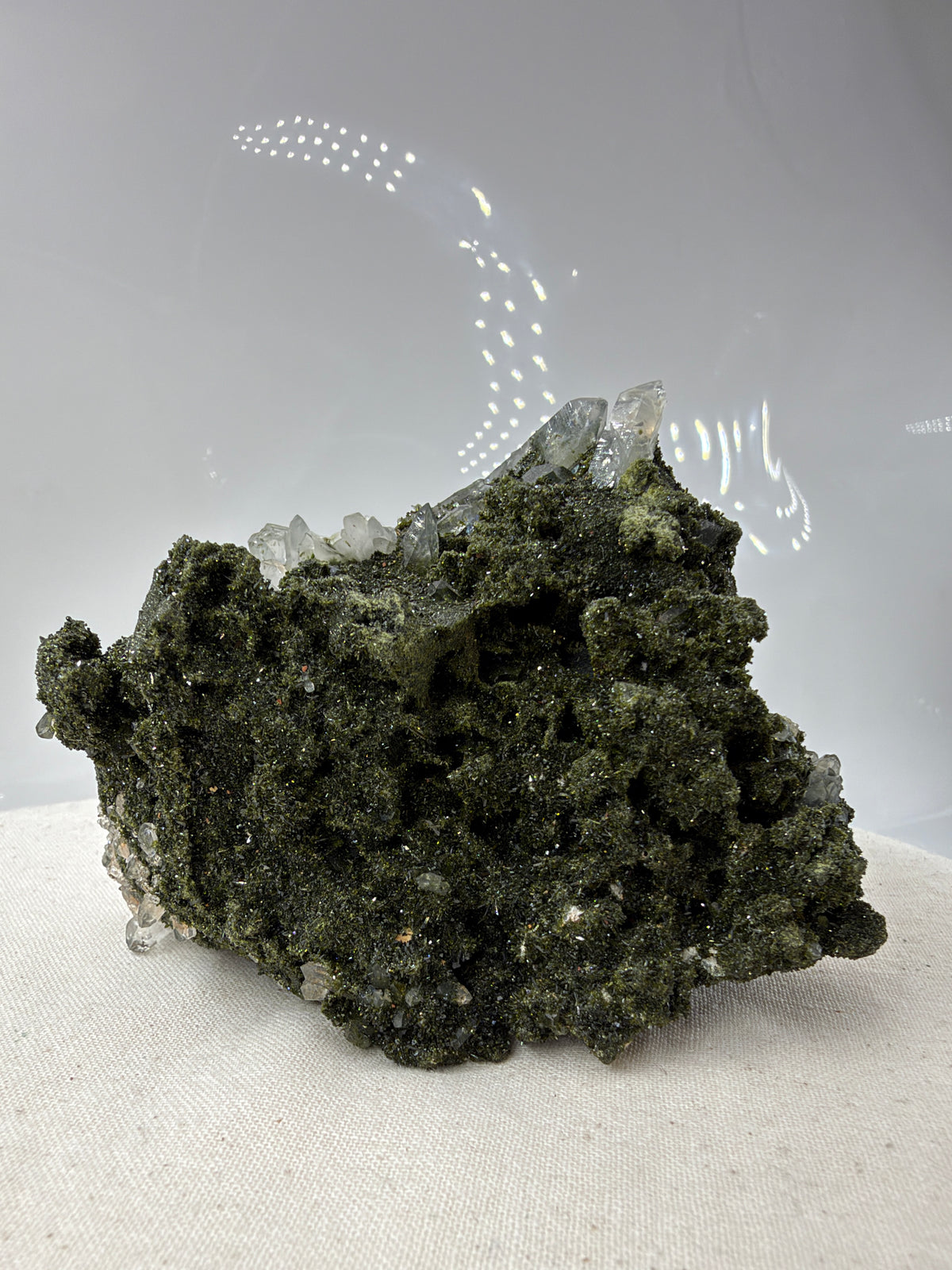 Epidotstufe ET108 mit olivgrüner, fein kristalliner Oberfläche und hellen, teils durchscheinenden Quarzspitzen
