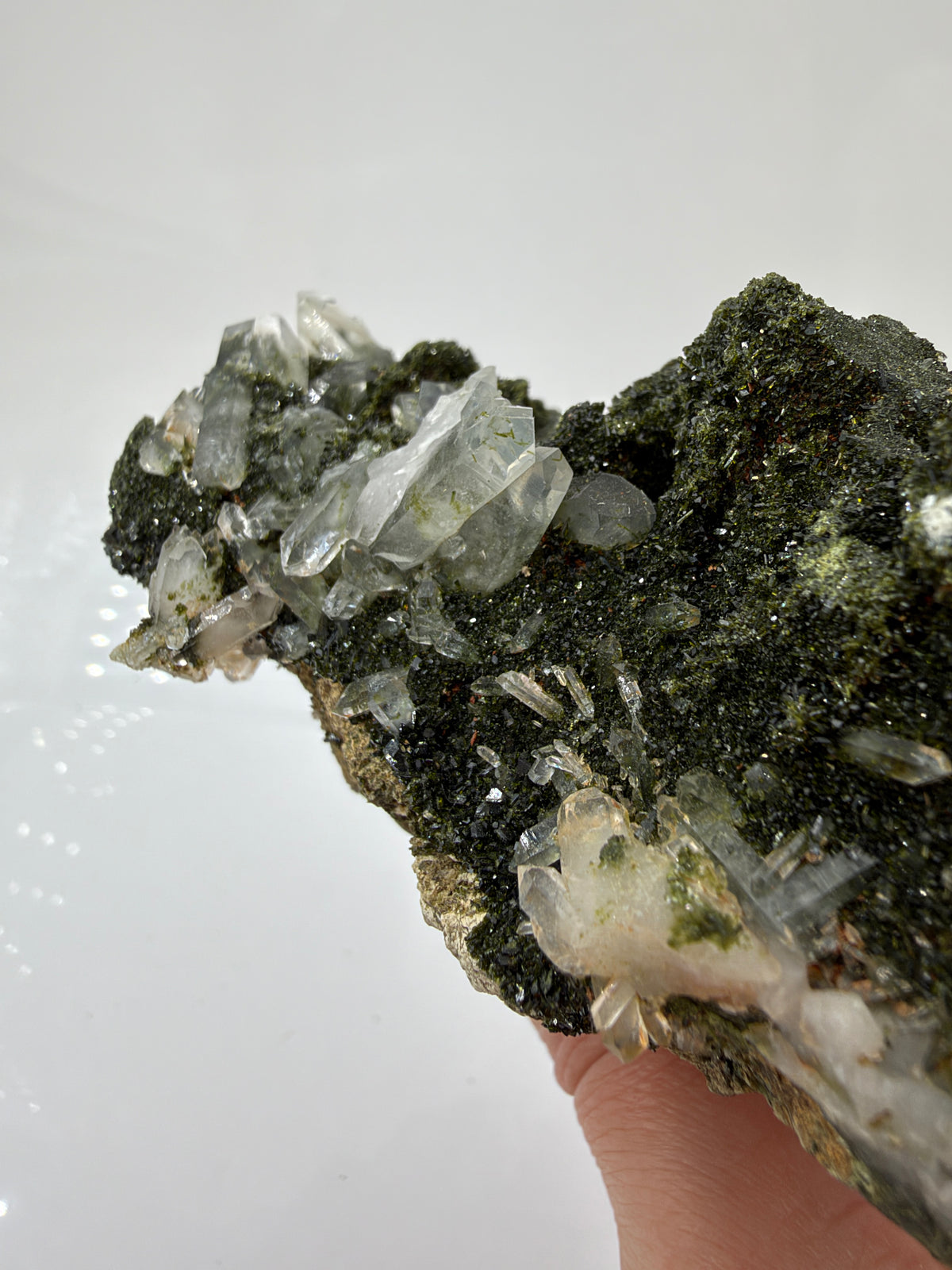 Epidotstufe ET108 mit olivgrüner, fein kristalliner Oberfläche und hellen, teils durchscheinenden Quarzspitzen