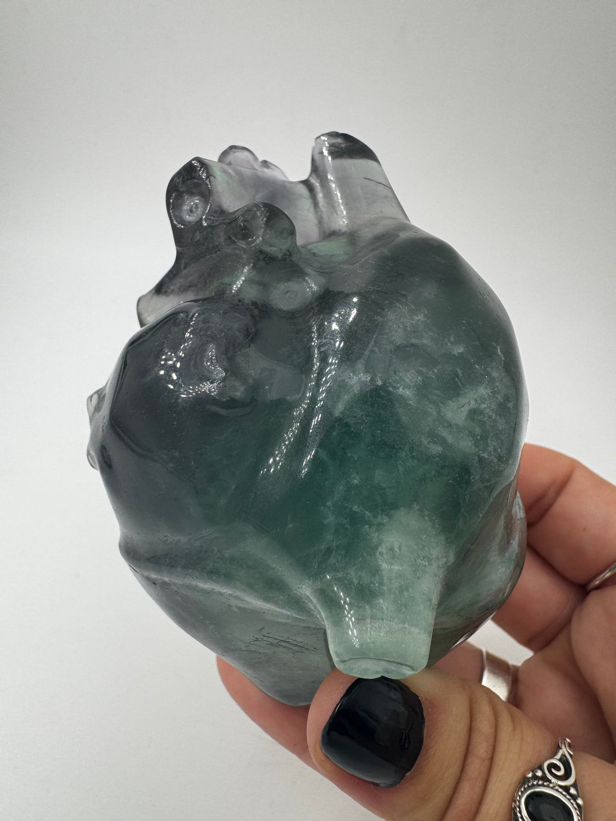 Ein anatomisch geformtes Herz aus Fluorit mit charakteristischen violett-grünen Farbbändern und einer hochglanzpolierten Oberfläche.