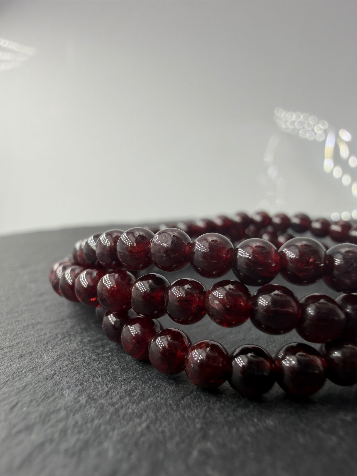 Dunkelrotes Kugelarmband aus poliertem Granat auf einem elastischen Band für Kinder.