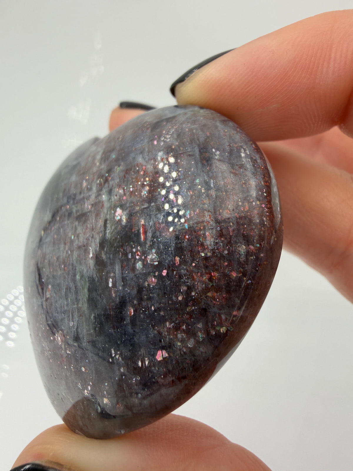 Ein Herz aus dunkelblauem Iolith, mit Sonnenstein. Die glatte Oberfläche zeigt je nach Lichteinfall einen metallischen Glanz und die charakteristischen Farbumschläge der beiden Mineralvarianten.