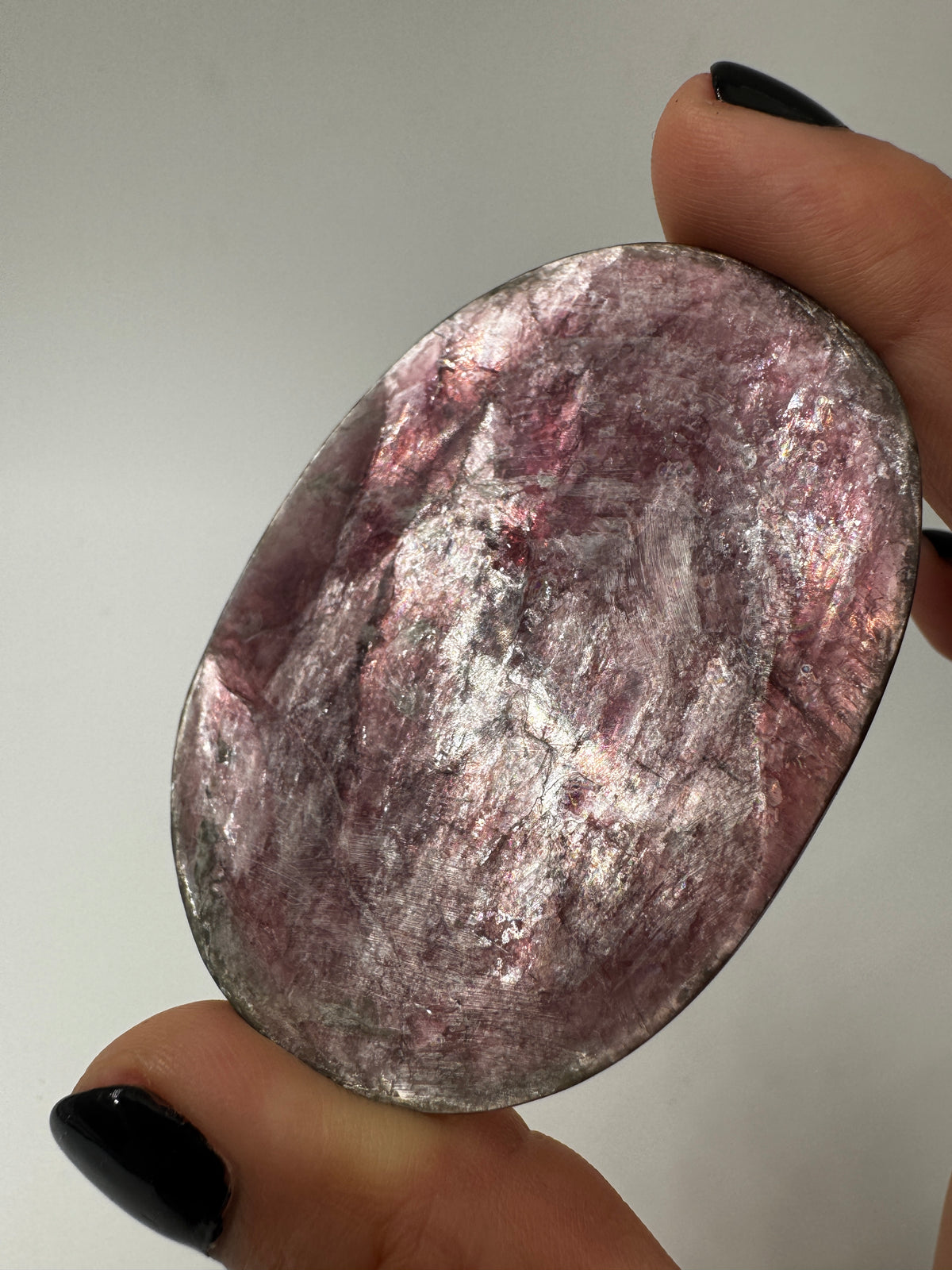 Ein glatt polierter, fliederfarbener Lepidolith-Handstein mit seidig glänzender Oberfläche und dezenten mineralischen Texturen.