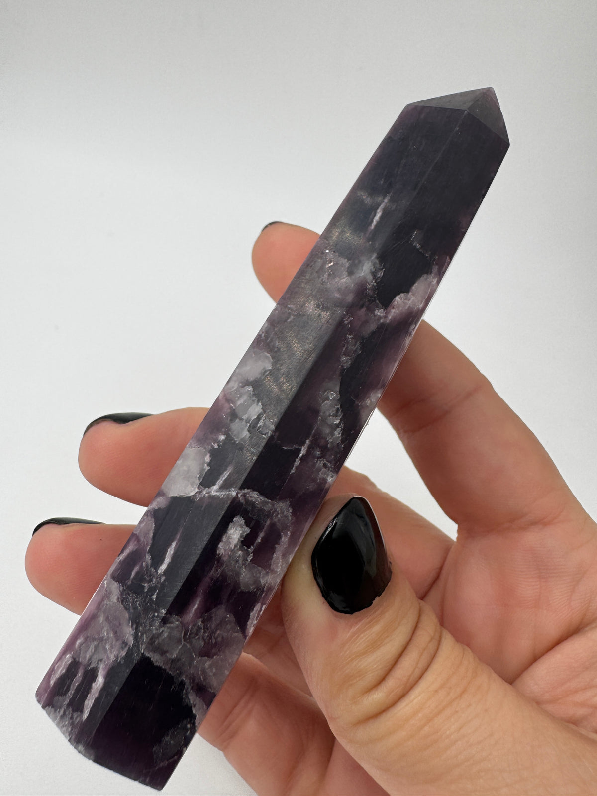 Ein spitz zulaufender, polierter Turm aus fliederfarbenem Lepidolith mit dezent glitzernden Glimmer-Einschlüssen