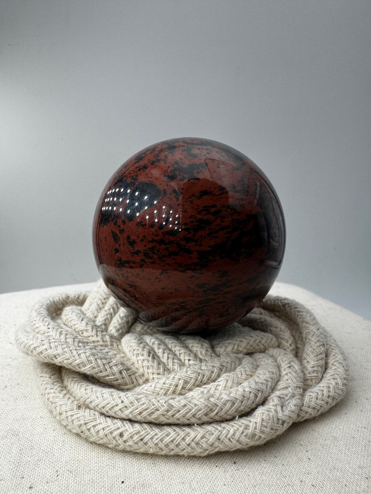 Polierte Kugel aus Mahagoni Obsidian mit rotbraun-schwarzer Maserung, Durchmesser 6 cm.