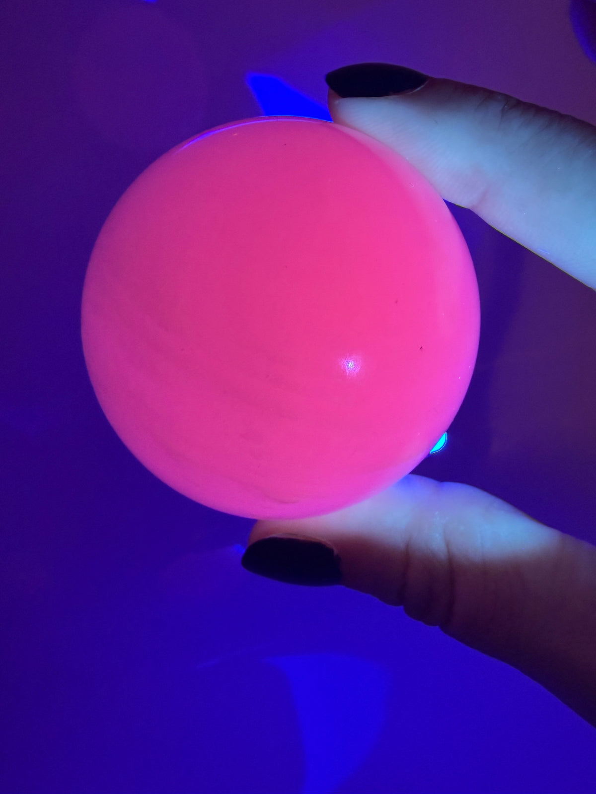 Handpolierte Mangano Calcit Kugel MK39 in zartrosa mit perlmuttartigem Glanz und UV-Fluoreszenz, Durchmesser 5,4 cm.