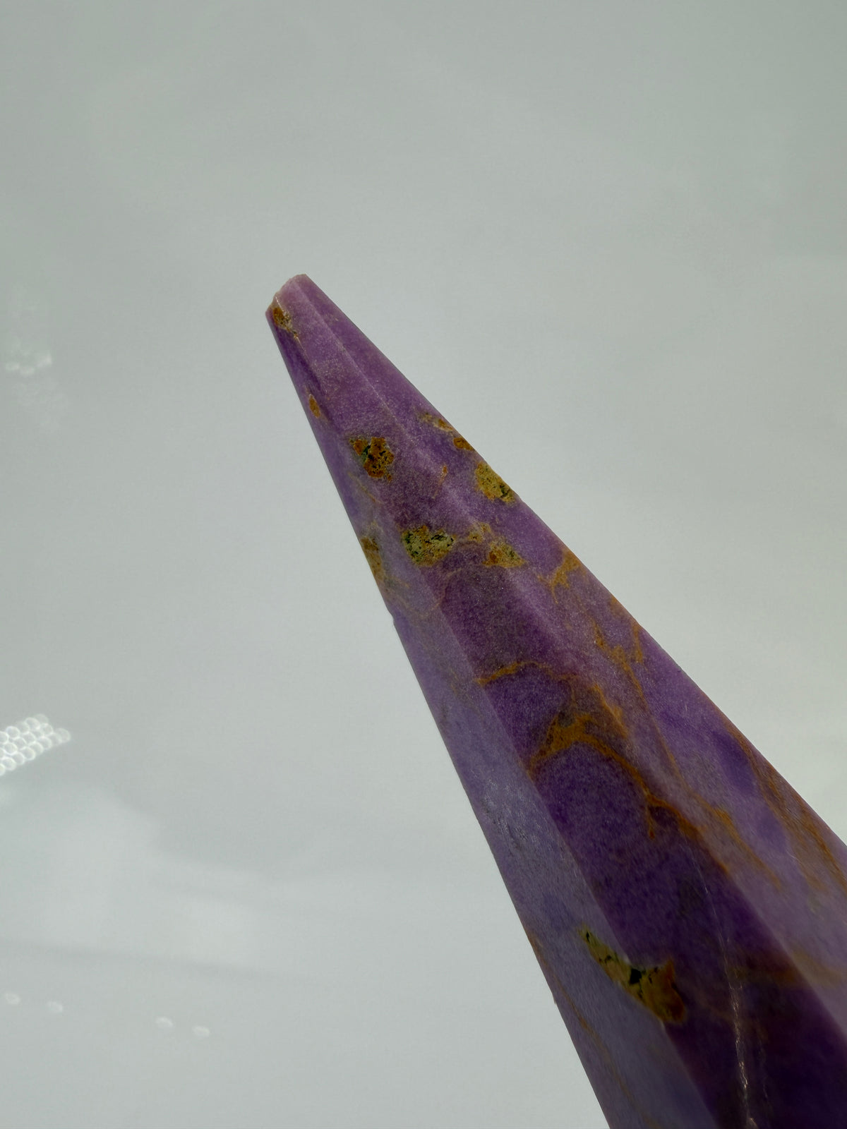 Eine fliederfarbene Phosphosiderit-Stele mit deutlich sichtbarer, natürlicher Bruchstelle an der Spitze und gelben Mineraladern.