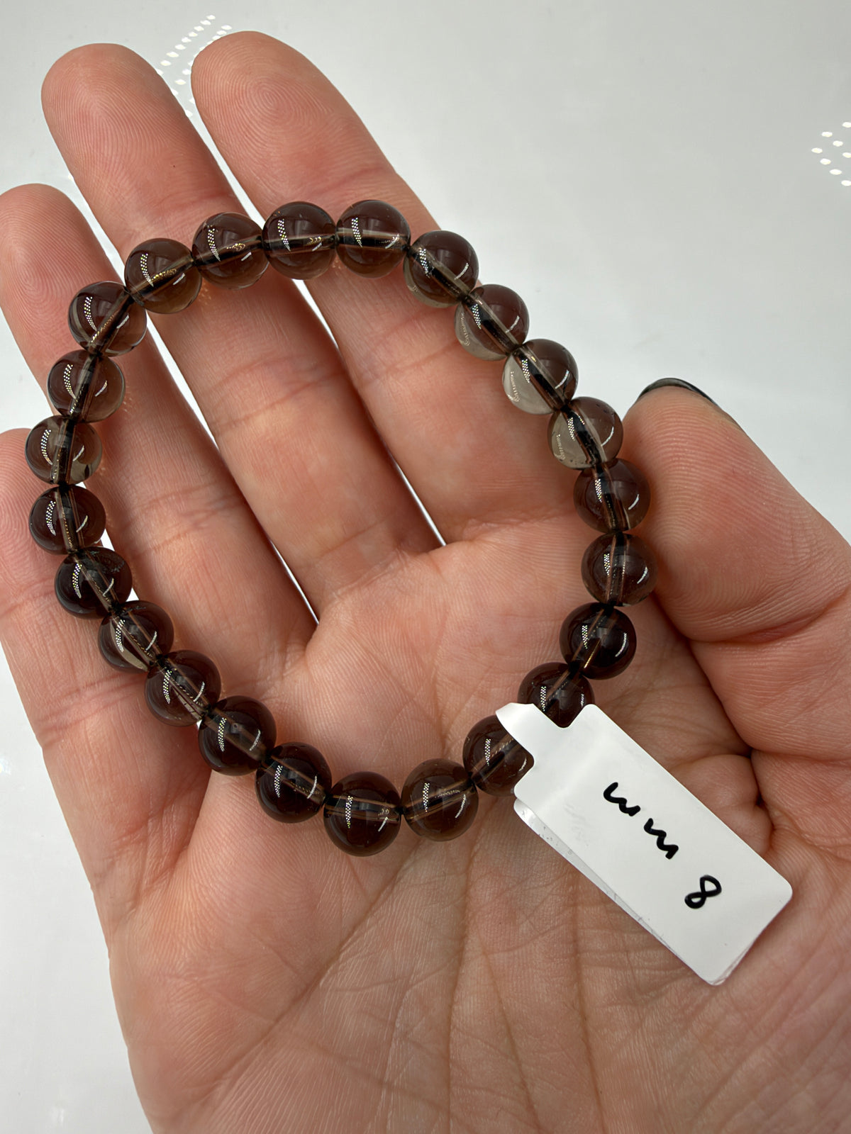 Rauchquarz-Armband RA12 mit braunen 8-mm-Kugelperlen auf einer offenen Hand.
