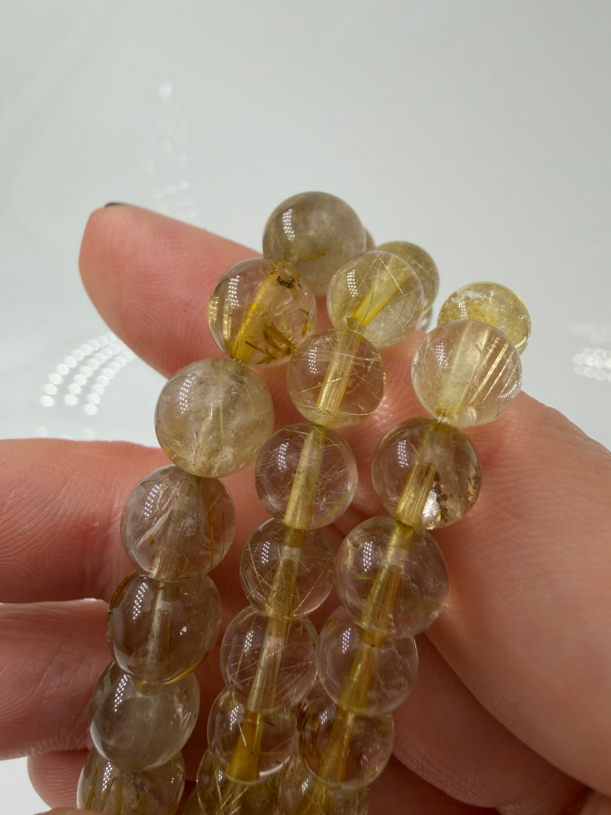 Nahaufnahme einer Quarzkugel mit metallisch glänzenden Rutil-Inklusionen (Venushaar).