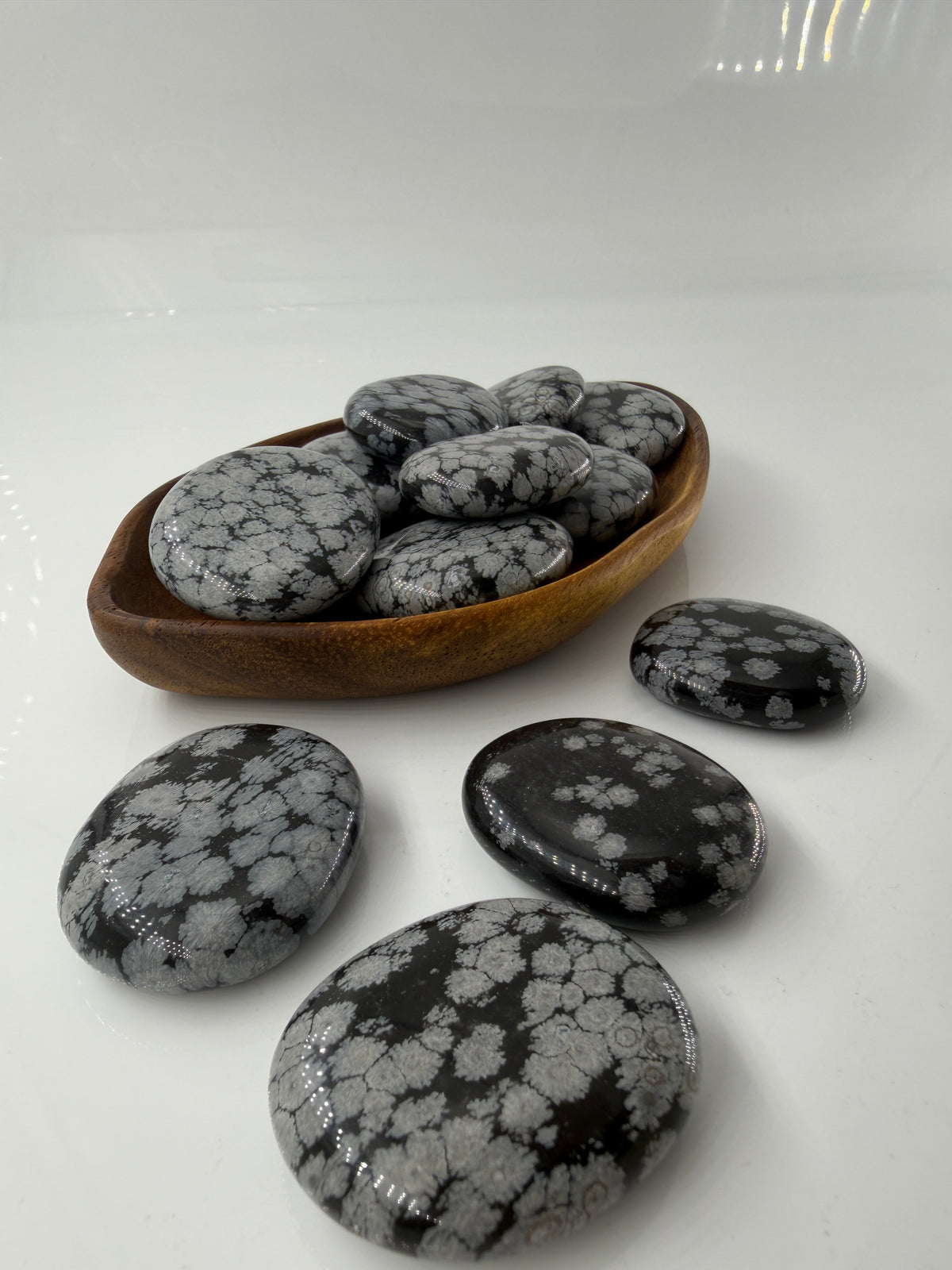Flacher Scheibenstein aus Schneeflocken-Obsidian mit markanten weißen Cristobalit-Flocken auf schwarzer Glasmatrix.