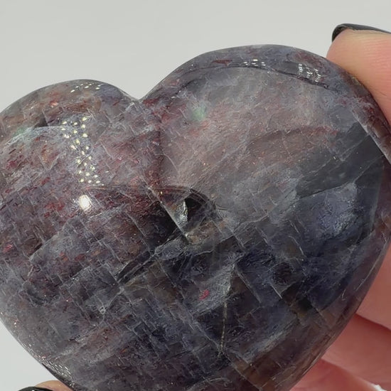 Ein Herz aus dunkelblauem Iolith, mit Sonnenstein. Die glatte Oberfläche zeigt je nach Lichteinfall einen metallischen Glanz und die charakteristischen Farbumschläge der beiden Mineralvarianten.