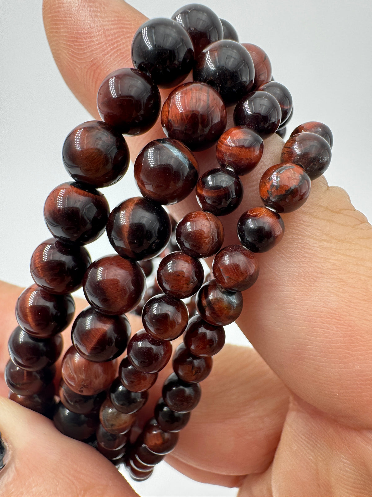 Nahaufnahme eines Kugelarmbands aus rotem Tigerauge mit glänzend polierten Perlen in tiefen Rot- und Brauntönen.